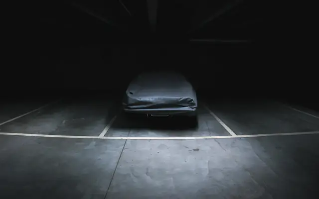 Abgedecktes Auto auf einem Stellplatz in einer dunklen Halle