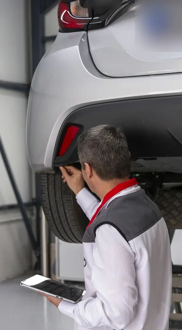 Begutachtung eines Autos auf der Hebebühne, Ergebnisse auf dem Tablet